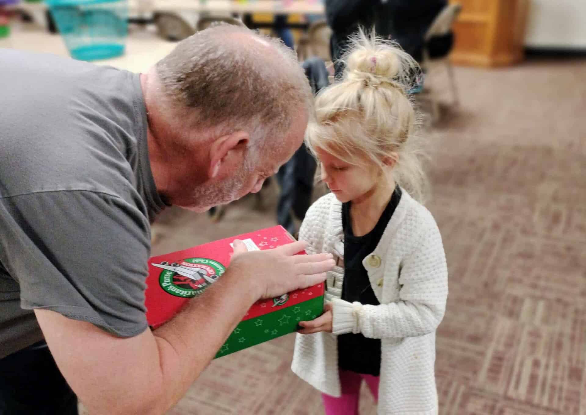 a man giving a little girl a gift